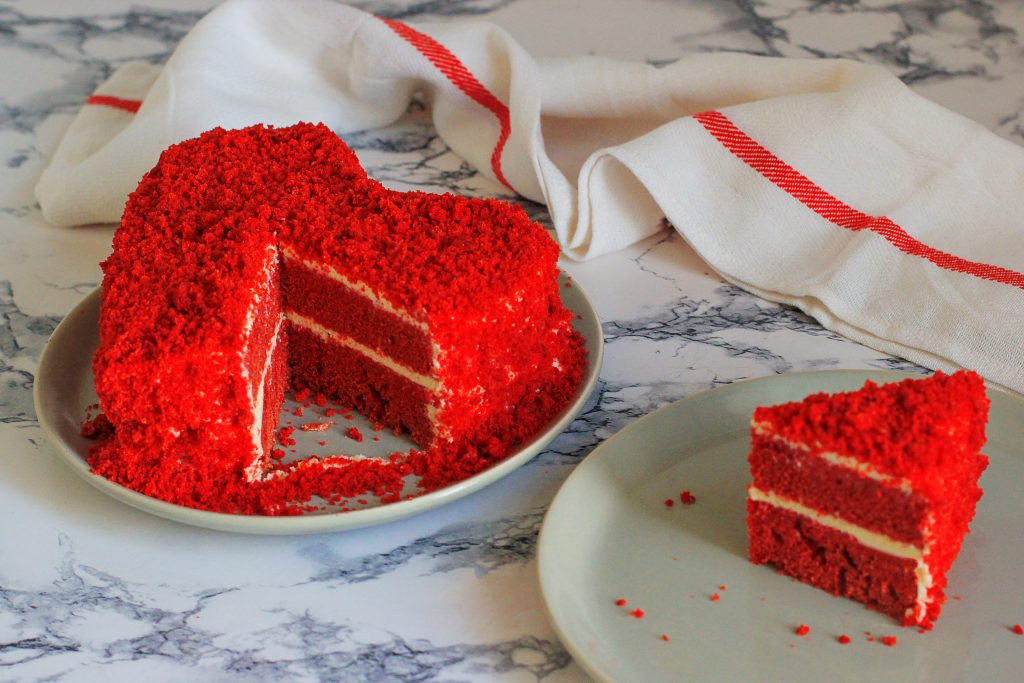 Heart shaped red velvet cake on marble table slice aside